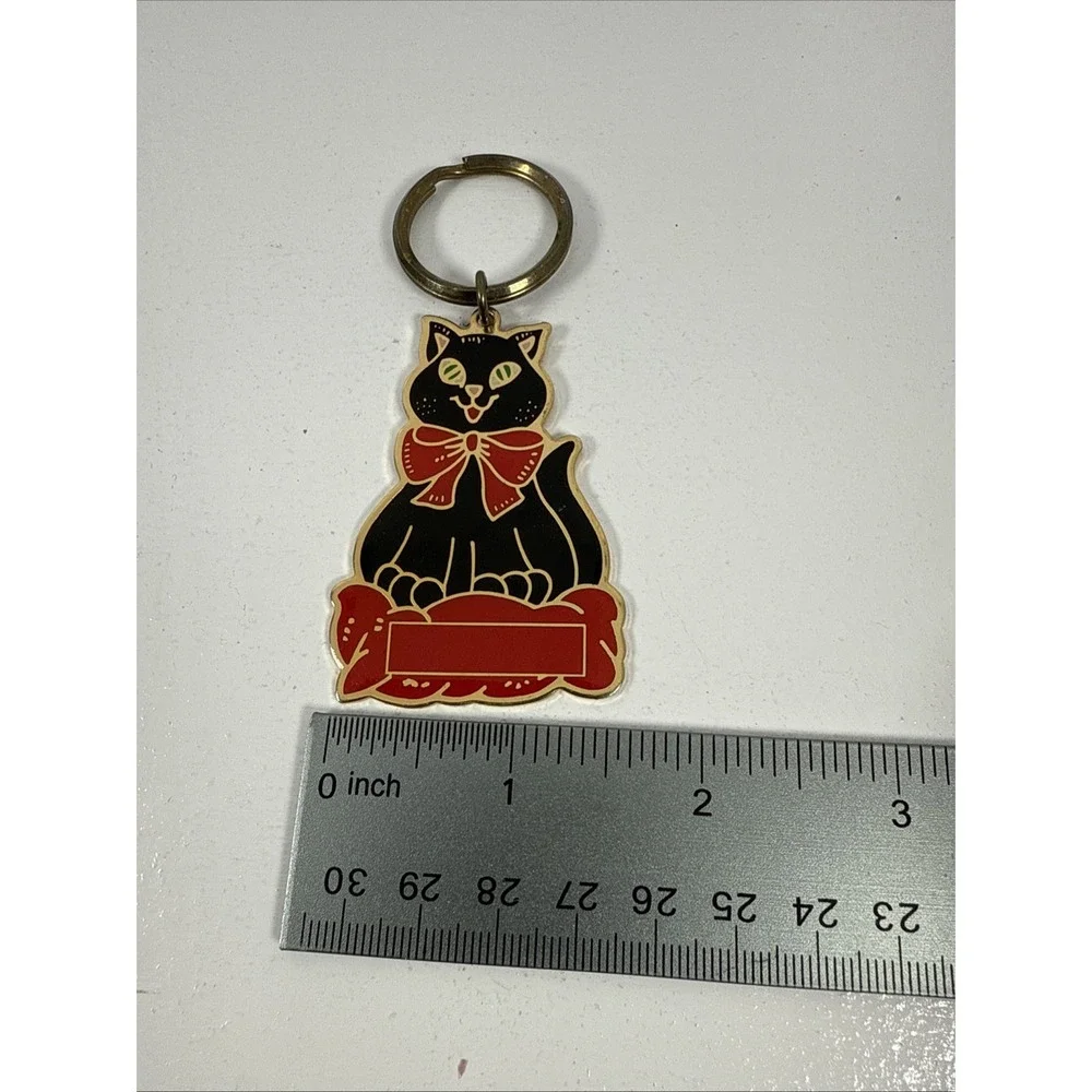 Black cat enamel keychain with gold-toned metal accents and‎ a red bow